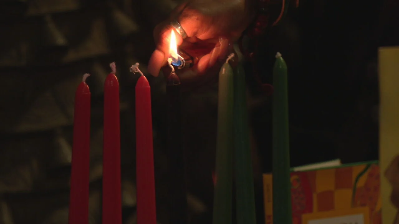 Image of a hand lighting the Kinara candle of Kwanzaa at the Roots 101 African American Museum in Louisville, Kentucky.